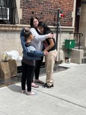 A teacher at the Guardian Angel School leans in to embrace two tearful students of hers. Since the school is closing for good, they will not return.