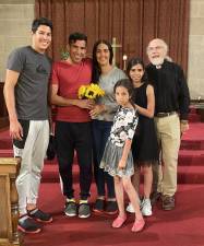 The Rev. K Karpen (right) with a recently arrived Venezuelan family. The parents were married in the church. Photo: Courtesy St. Paul &amp; St. Andrew