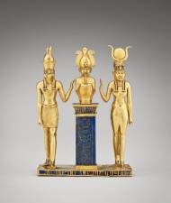 From “Divine Egypt,” at the Met: Statuette of falcon-headed Horus, seated Osiris, and Isis, wearing sun disk and horns. Made of glass, gold, and lapis lazuli, it dates from ca. 872 to 837 BCE. About 4 inches tall, it is on loan to the Met from the Musée du Louvre.