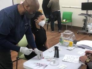 Ronnie Moore of Allure Specialty Pharmacy provides a vaccine to Melissa Johnson-Bowen, director of Project FIND’s Hamilton Senior Center. Photo courtesy of Project FIND