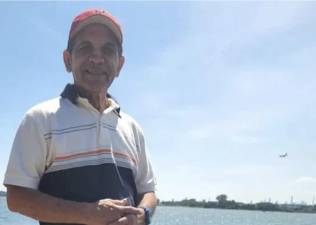 Morton Williams stock clerk Leobardo Hernandez in happier times on Jamaica Bay, a plane landing at JFK airport behind him.