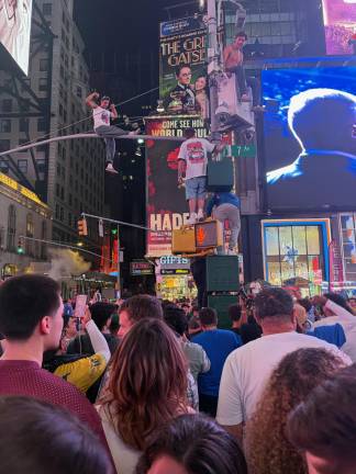 One fan in Times Square climbs atop a street lights while celebrating.