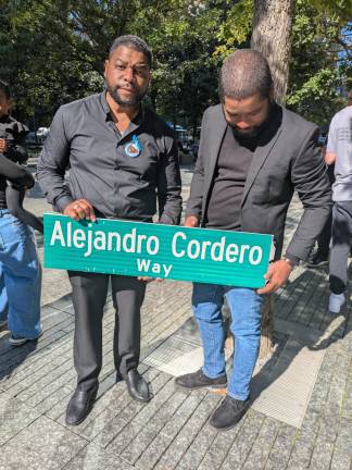Street co-naming sign Alejandro Cordero Way, held by his brothers, Moises Vladimir and Wellington.