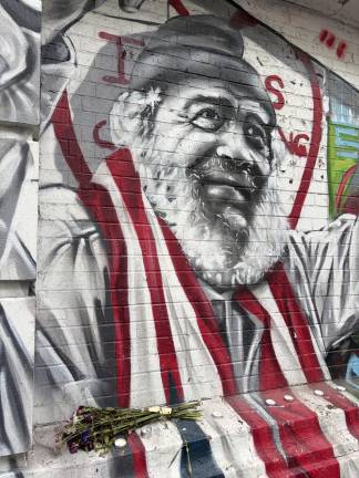 Carlos “Chino” Garcia draped in Puerto Rican flag on a mural at P.S. 64 / Charas on East 10th Street.