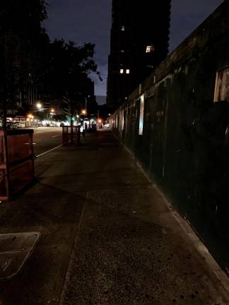 A view looking north up the east side of First Ave. from the corner of East 79th St. The entire darkened block near an Extell construction fence is forbidding and spectral in appearance, and though it's only 9 p.m., not a single pedestrian is in sight.