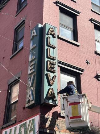 Workers prepare to take down the Alleva Dairy sign on March 1, the last day the inconic cheese store will be open in Little Italy, where it has operated for 103 years, before moving lock stock and sign to Lyndhurst, N.J. Photo: Angela Barbuti.