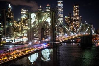 At a COVID-19 Day of Remembrance ceremony in Brooklyn on Sunday, March 14, 2021, images of some New Yorkers lost to the pandemic were projected onto the Brooklyn Bridge. Photo: Michael Appleton/Mayoral Photography Office