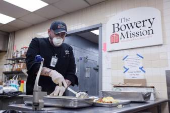 Bowery Mission staff member Raffaele DePalma dons a mask and gloves to dole out food to residents. Since last March, Bowery Mission has formed a health and safety task force that had “led all of their efforts to respond effectively under the latest guidelines,” said Bowery Mission president and CEO James Winans. Photo: Jeffrey Lau