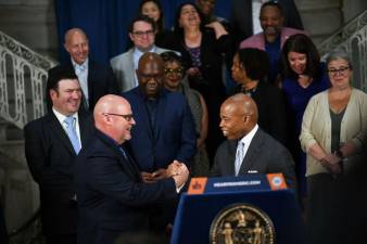 Mayor Eric Adams (at lectern) and UFT president Michael Mulgrew clasp hands after reaching a new tentative five year pact between the city and the teacher’s union. Photo: Mayors Photography Office