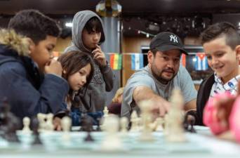Russ Makofsky (center) has a passion for teaching chess that he’s shared with the kids of asylum seekers while also sending thousands of donated chess sets to Africa. Photo: Noah Augustin