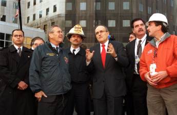 NYC Mayor Rudolph Giuliani (third from right) describes the clean-up operation at the site of the World Trade Center terrorist attack in lower Manhattan to Secretary of Defense Donald H. Rumsfeld (second from left) on Nov. 14, 2001. Photo: Department of Defense photo by R. D. Ward, public domain, via Wikimedia Commons