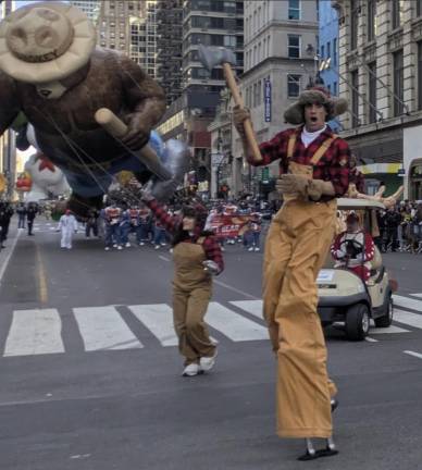 Stilt-walking lumberjack guides Smokey Bear and his balloon handlers.