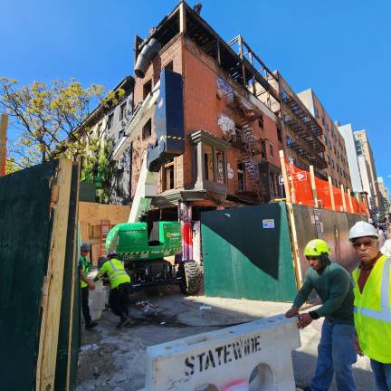 Workers set about tearing down the long empty fire damaged buildng at 210 Seventh Ave., on orders of the Department of Buildings.