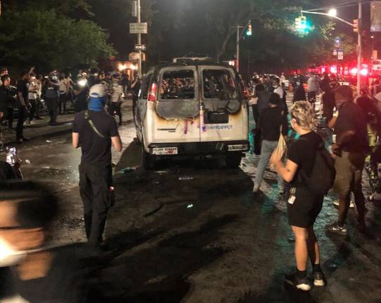 Protesters stand near a burned New York City Police Department van in Brooklyn, Friday, May 29, 2020. Demonstrators took to New York City streets on Friday for a second day to protest the death of George Floyd, the black Minnesota man killed in Minneapolis police custody.