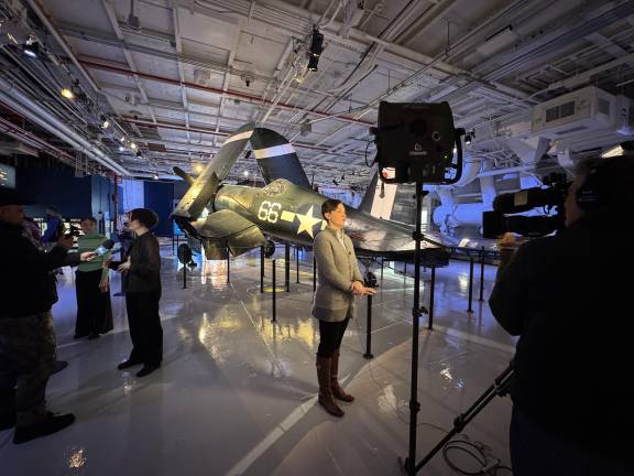 Jessica Williams, left, in black, and Kate Good, right, in gray, conduct interviews in front of the Corsair, highlighting its history and importance to the story of <i>Intrepid</i>.