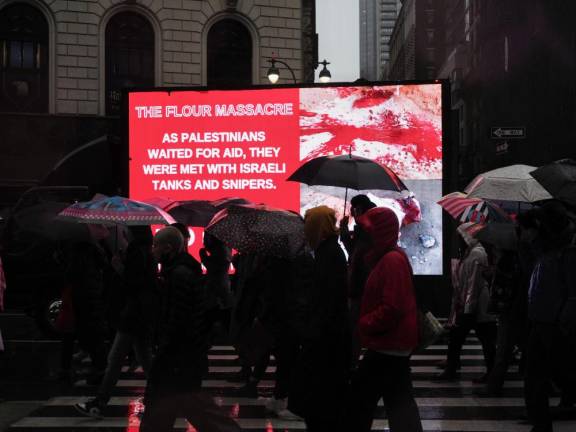 Protesters march down Sixth Avenue next to a truck displaying grisly photographs from the “Flour Massacre,” when at least 118 Palestinians were killed by Israeli gunfire while attempting to get food from aid trucks in Gaza.