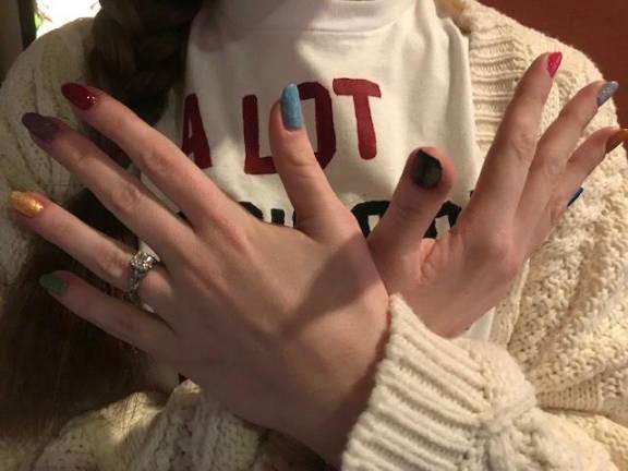 A fan named Allison shows off her painted fingernails, made to match the color of Taylor Swift’s ten albums. Photo: Marie Pohl