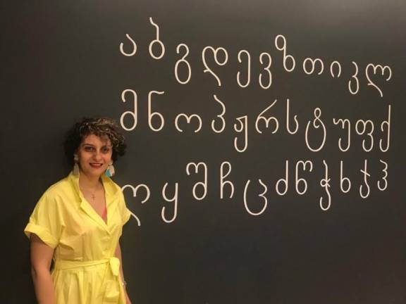 Photo: Diana DuCroz. Owner Tamara Chubinidze, next to the modern Georgian alphabet painted on the restaurant wall.