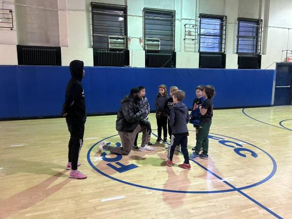 Kids gather round coach Eric at the start of one of their last practice sessions in the gym.