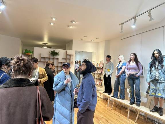 The models stand on wooden benches displaying some of Camille’s original pieces