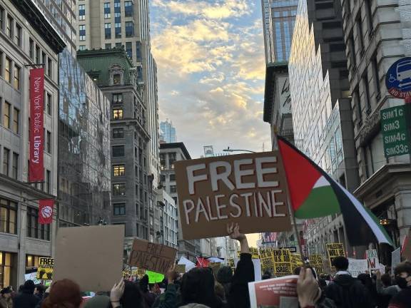 Palestinian supporters marching down 34th Street holding their flags and “Free Palestine” signs.