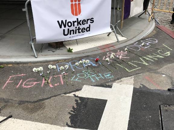 <b>Roses were laid atop the sign, “Pray for the Dead. Fight for the Living” just feet away from the still standing Triangle Shirtwaist Factory where 146 people died in the tragic fire in 1911</b>. Photo: Keith J. Kelly