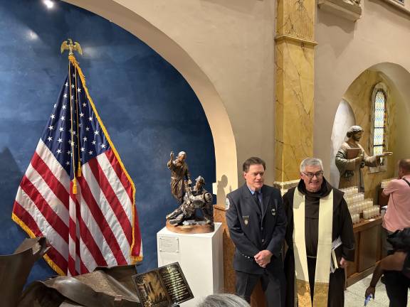Retired firefighter and artist Dennis Burke and Father Jordan beside Burke’s sculpture, “Brotherhood 9/11.”