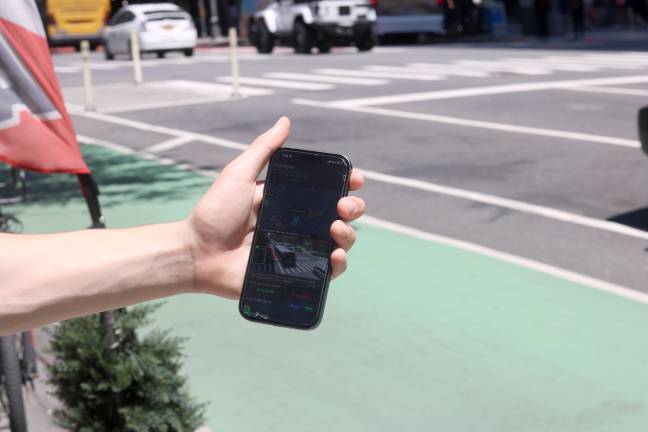 ParkSignal NYC detects open street parking spots. Eighteen-year-old Theo Darringer holds his phone in front of the free spot the app says is open.