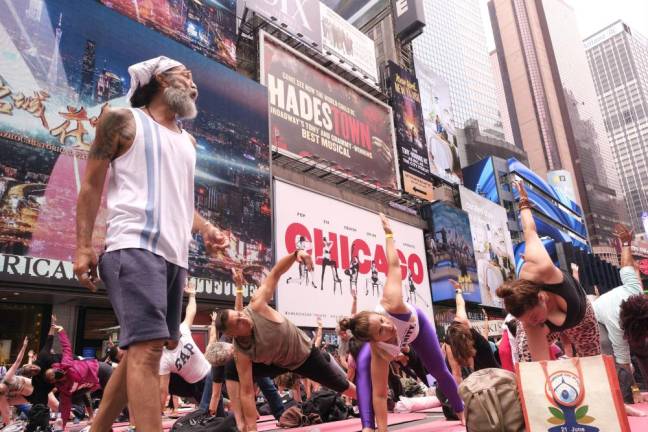 Billboards from some Broadway hits form the backdrop to the Summer Solstice Yoga: Mind Over Madness event in Times Square on June 21. Photo: Beau Matic