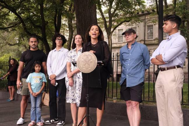 District 2 Council Member Carlina Rivera speaking at a press conference in front of City Hall, where she hailed the passage of a bill that will force the NYC Department of Transportation to establish a real-time bike map for riders. Shawn Garcia (black shirt) is pictured on her left with his daughter, with bicycle advocate Jon Orcutt (wearing cap) on her right.