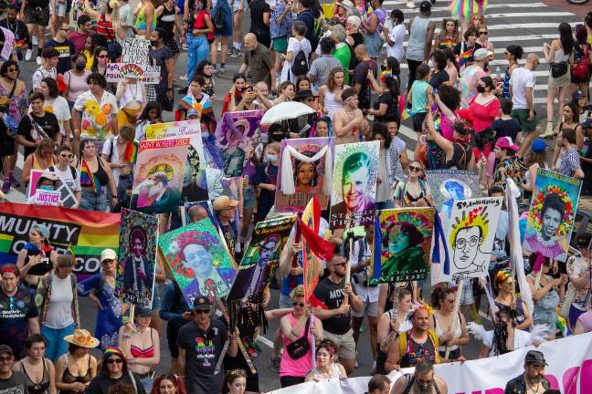 Marchers carry signs of different LGBT+ saints at Pride 2021. Photo: Trish Rooney