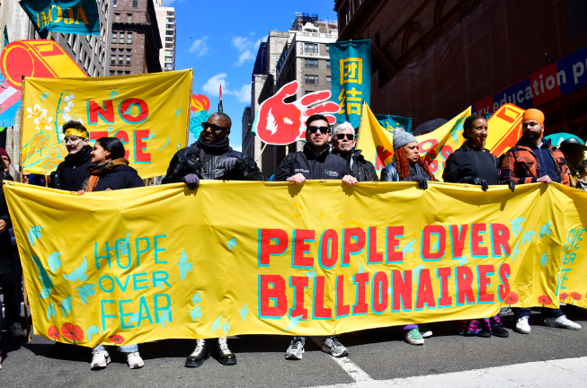 A sign from an earlier protest, “People over Billionaires” returns for another run in the larest “No Kings” demonstration yet in Manhattan on March 29.