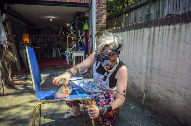 Rachel Berry works in the driveway to her New York garage studio, refinishing a chair she will turn into art.