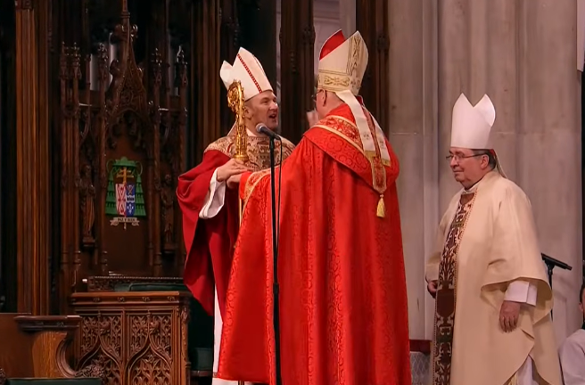 Cardinal Timothy Dolan passes the bishop’s staff to newly installed Archbishop Ronald Hicks during the installation Mass at St. Patrick’s Cathedral Feb. 6.