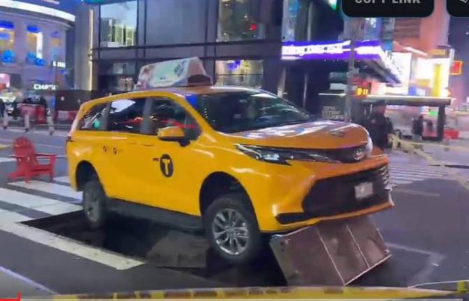 A taxi sits atop a metal grate in Times Square.