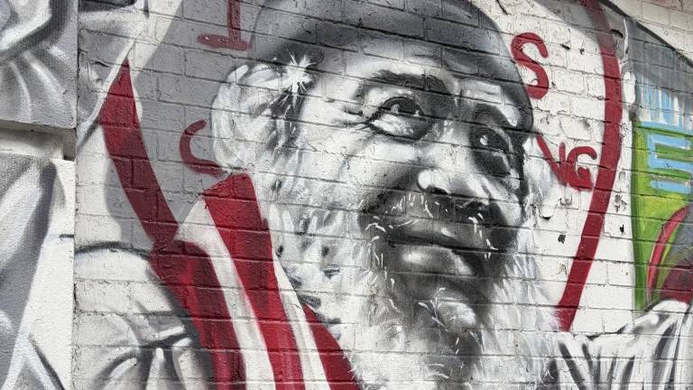 Carlos “Chino” Garcia draped in Puerto Rican flag on a mural at P.S. 64 / Charas on East 10th Street.