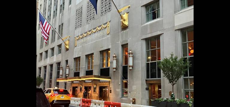 Lexington Avenue entrance of the Waldorf Astoria hotel’s landmarked exterior, with the two-story Lex Yard restaurant gleaming behind the windows on the right.