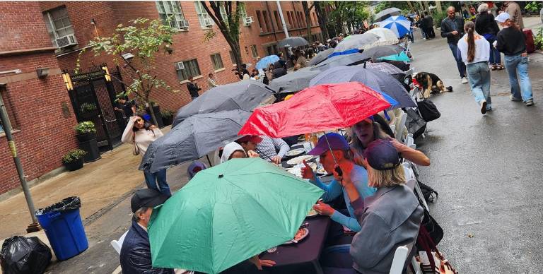 Umbellas go up as a light rain falls for a short time on the Longest Table in Chelsea on Oct. 4.