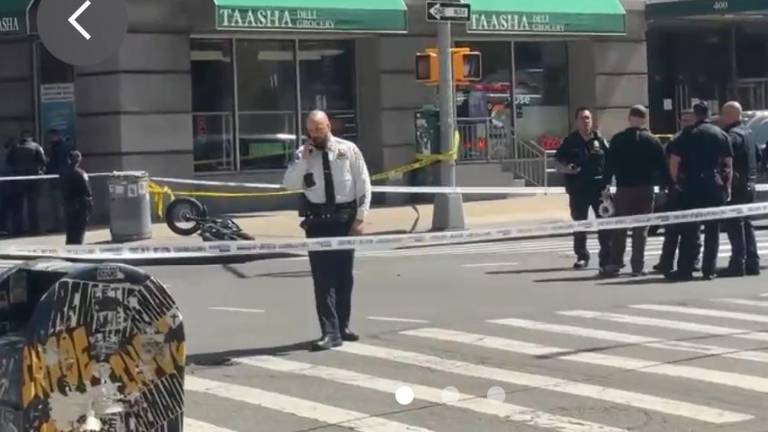 Police at scene of a fatal accident where an e-biker was knocked from his vehicle after he was doored by a parked passenger van and subsequently fell under the rear wheels of a tequila delivery truck. The e-bike he was riding west on Broome St. is visible in the rear.