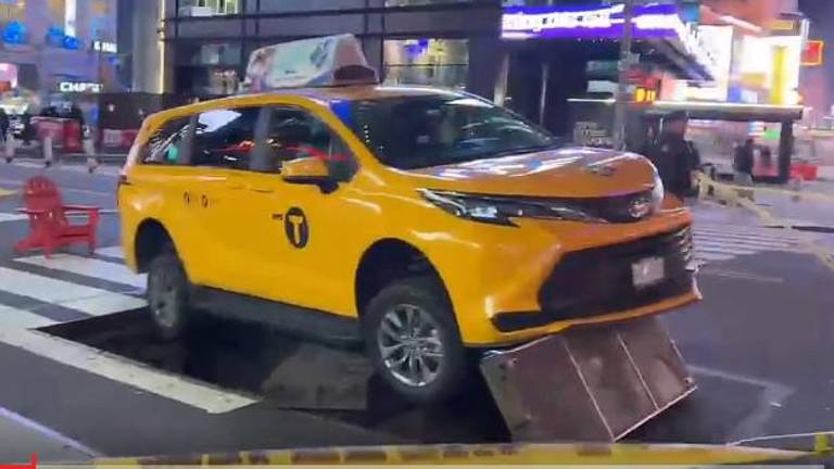 A taxi sits atop a metal grate in Times Square.