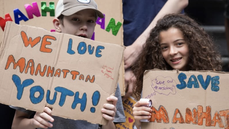 students and family members showcasing signs to show support to this local cause at a City Hall rally on June 15.